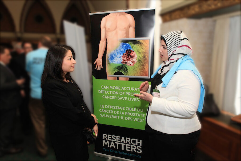 Two female researchers engaged in conversation at a conference next to a banner that reads "Research Matters."