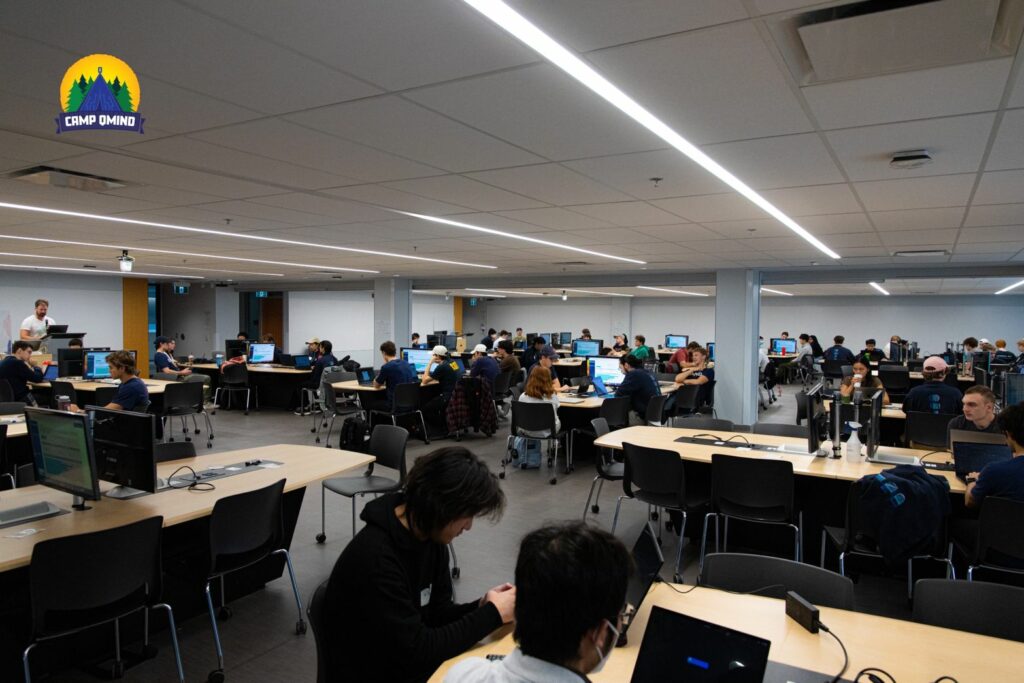 Photo from the Camp QMIND Hackathon event. A large computer lab is filled with students, all with their heads down, looking at their computers and focusing.
